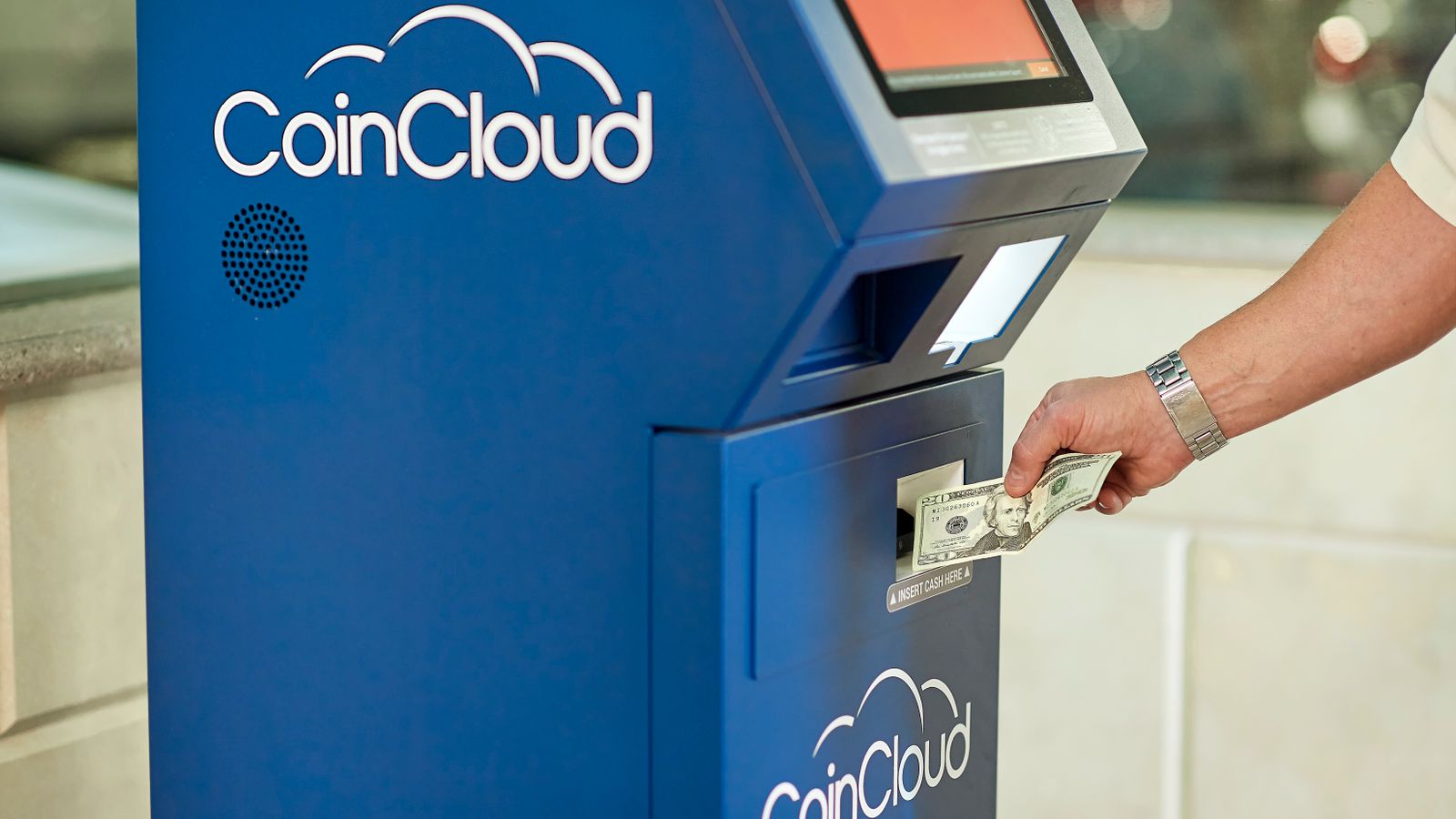 Utilisateur insérant des billets dans un crypto ATM pour une transaction en cryptomonnaie, illustrant les obligations AML applicables en Belgique