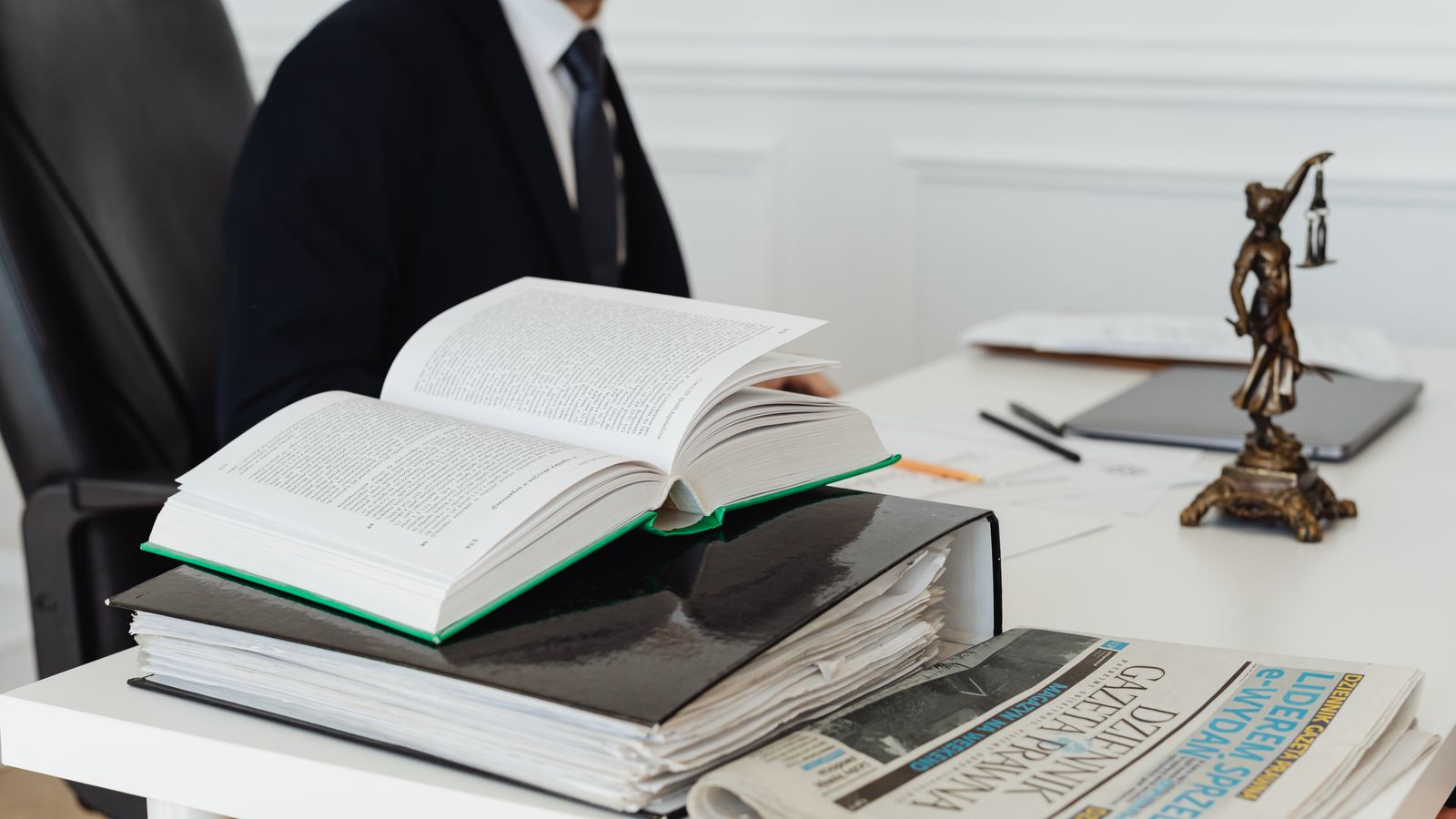 Juriste consultant des ouvrages de droit et des documents sur un bureau, illustrant le débat juridique autour de l'exemption AML de la Loterie Nationale belge